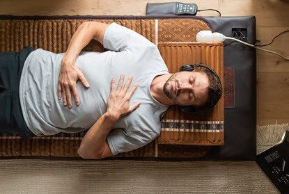 Person lying on BioMat and the BioAcoustic Mat Duo