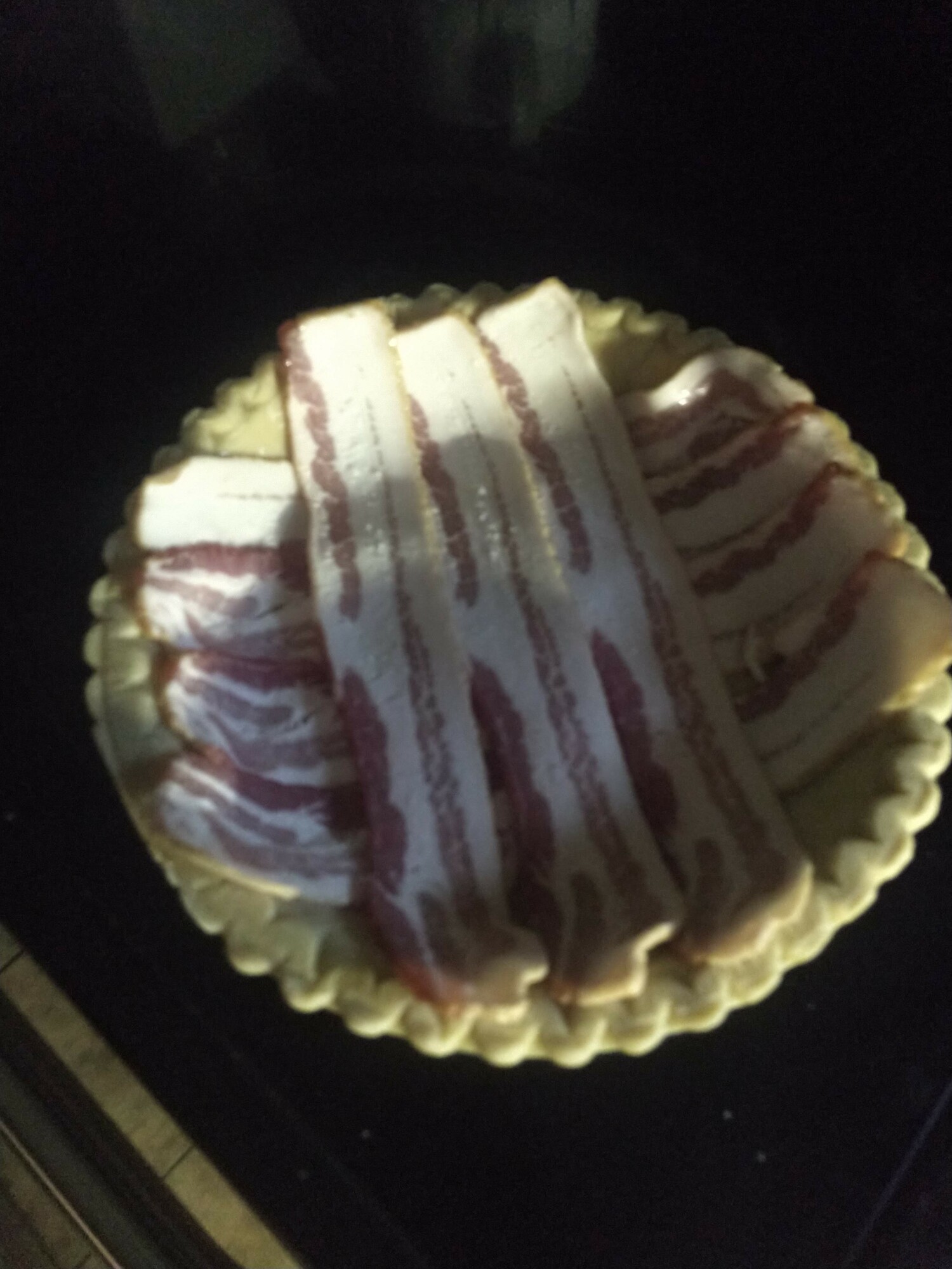 Frozen pie crust with uncooked bacon layered on it