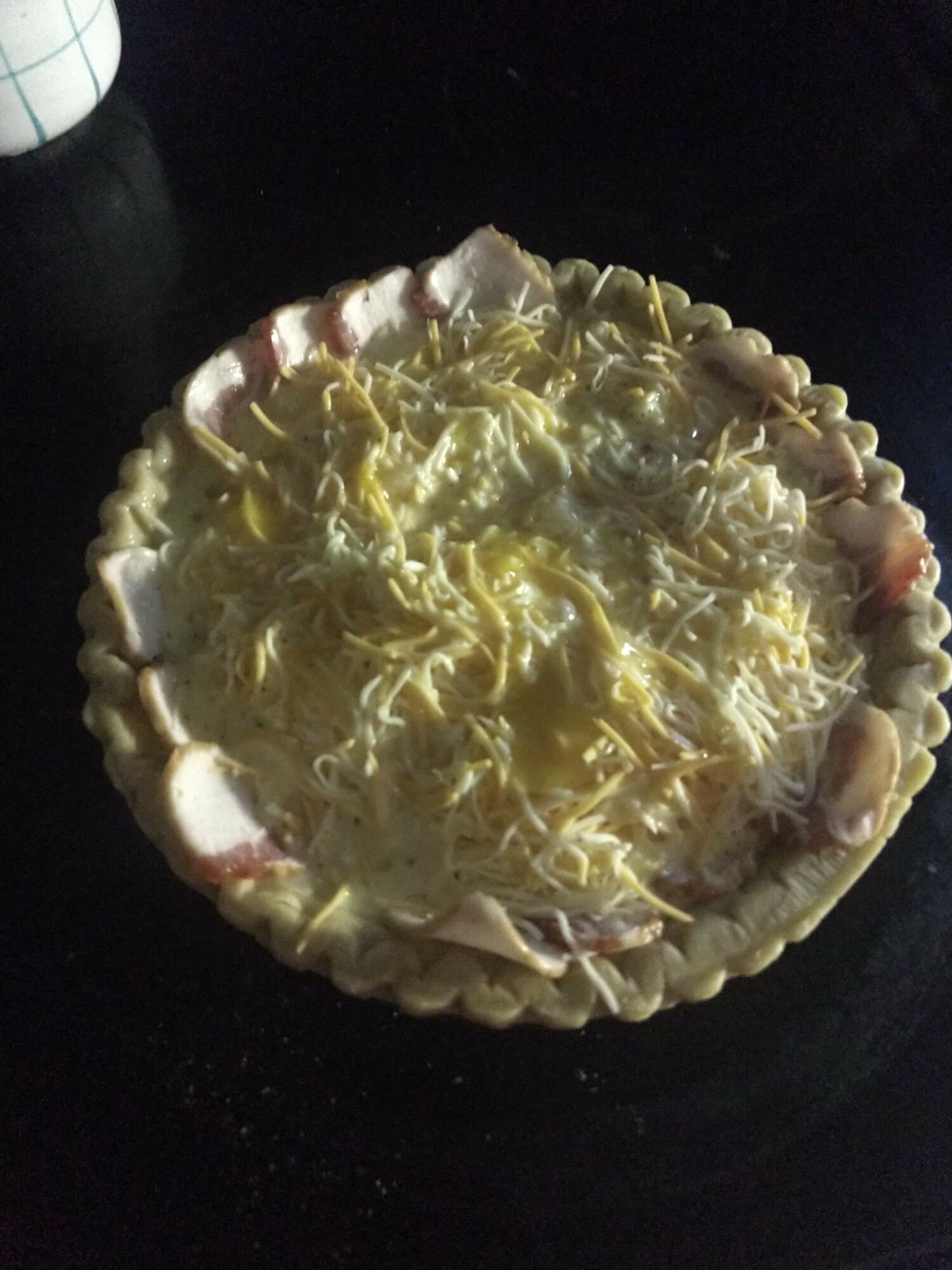 Prepared quiche with shredded cheese on top