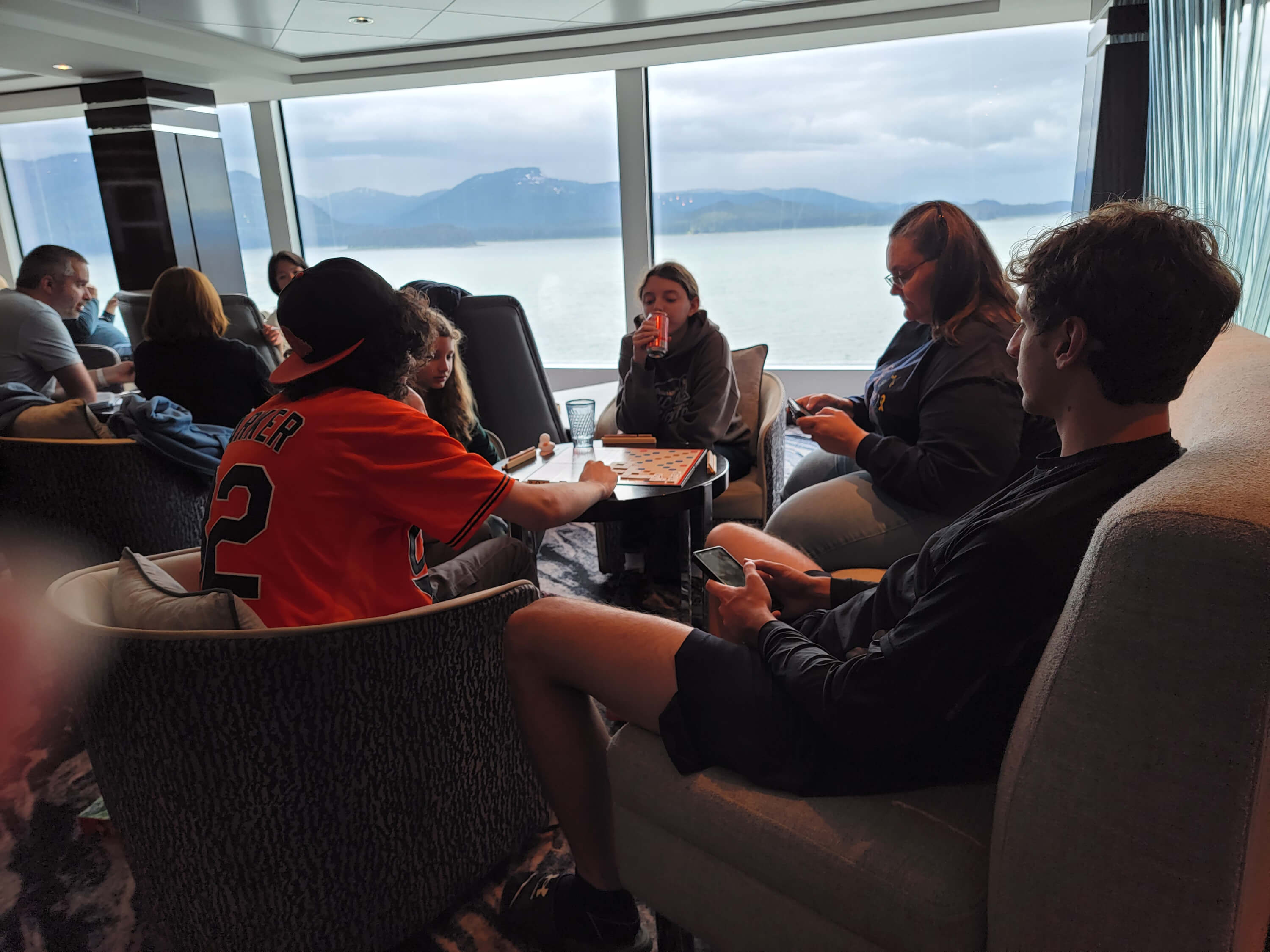 family playing games sitting by a window as we pull out of port