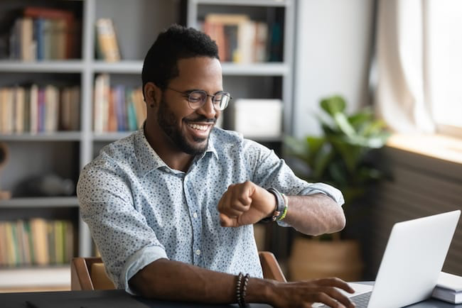 Man working from home looks at his watch