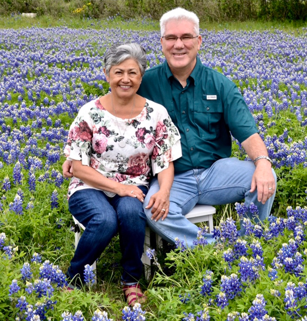 A person and person sitting in a field of flowersDescription automatically generated