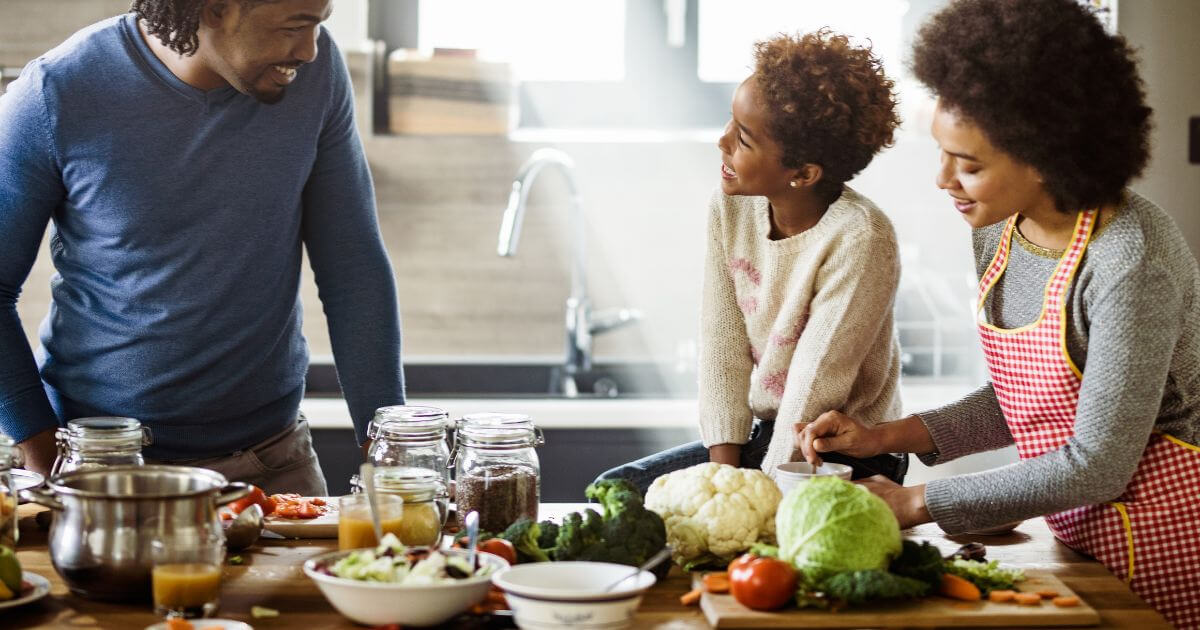 A happy family preparing a meal with prebiotic foods in their kitchen.