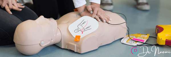  Hands placing AED pads on a manikin's chest during a defibrillation demonstration in Albufeira