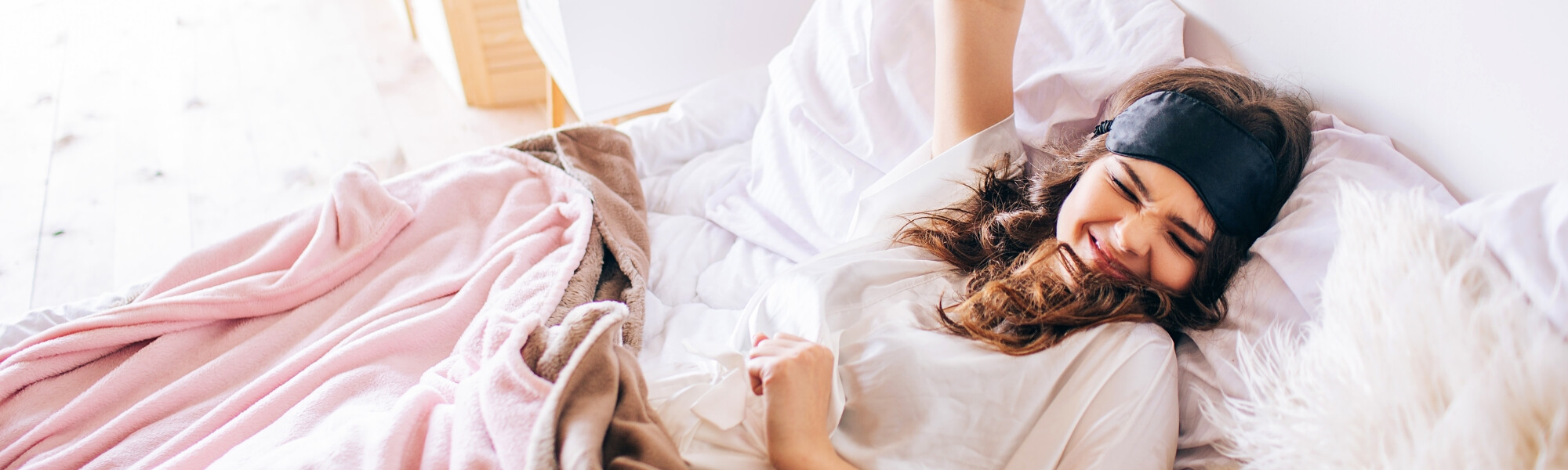 Image of a woman waking up happy and content: "Happy woman waking up in the morning feeling refreshed and stress-free after following a healthy morning routine.