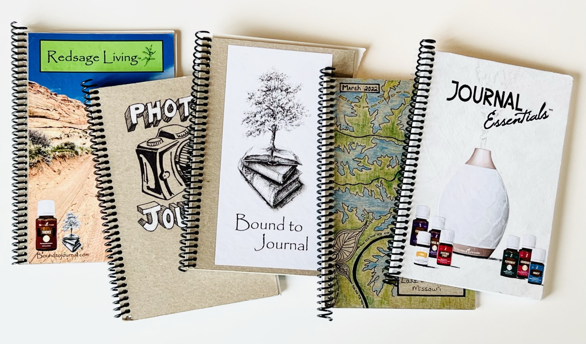 Bound to Journal examples of journals that travel with us at all times.  Our Photo Journal, Journal Essentials for essetial oil information, our business Redsage Living LLC journal, notes along the road, and our Bound to Journal plans for articles, social media, etc.
