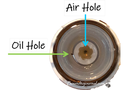 top view of an essential oil bottle reducer showing two holes labeled with air hole and oil hole