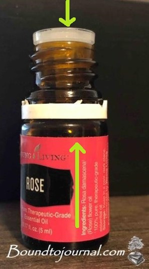 A bottle of Young Living Rose essential oil with two arrows drawn to indicate the location of the oil hole