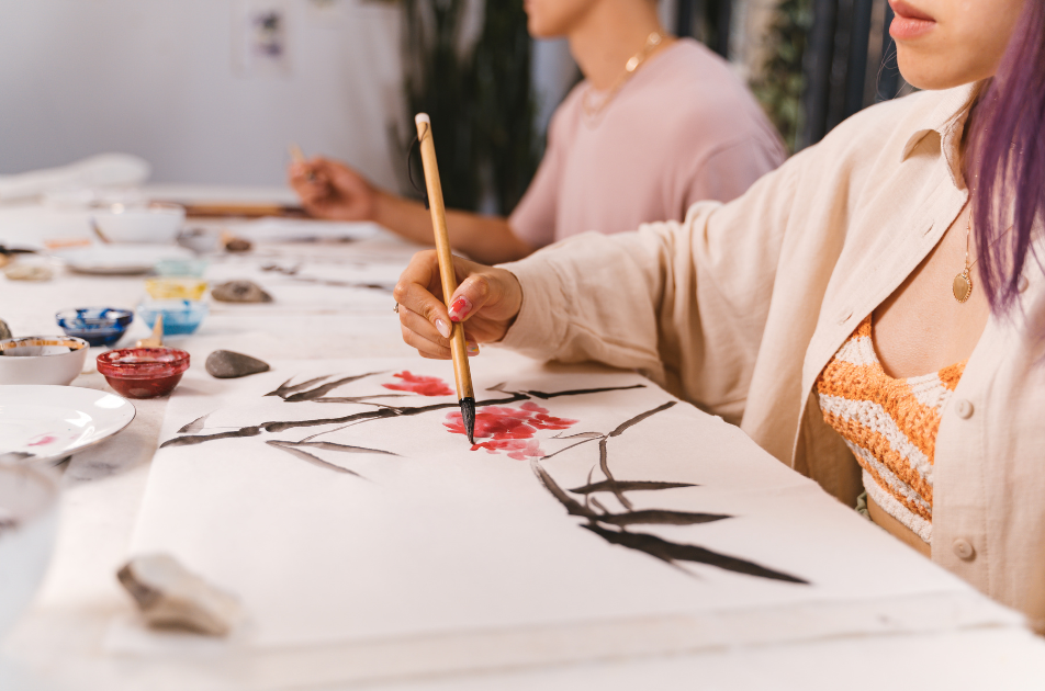 Two people in calm space japanese paint brush painting flowers and leaves