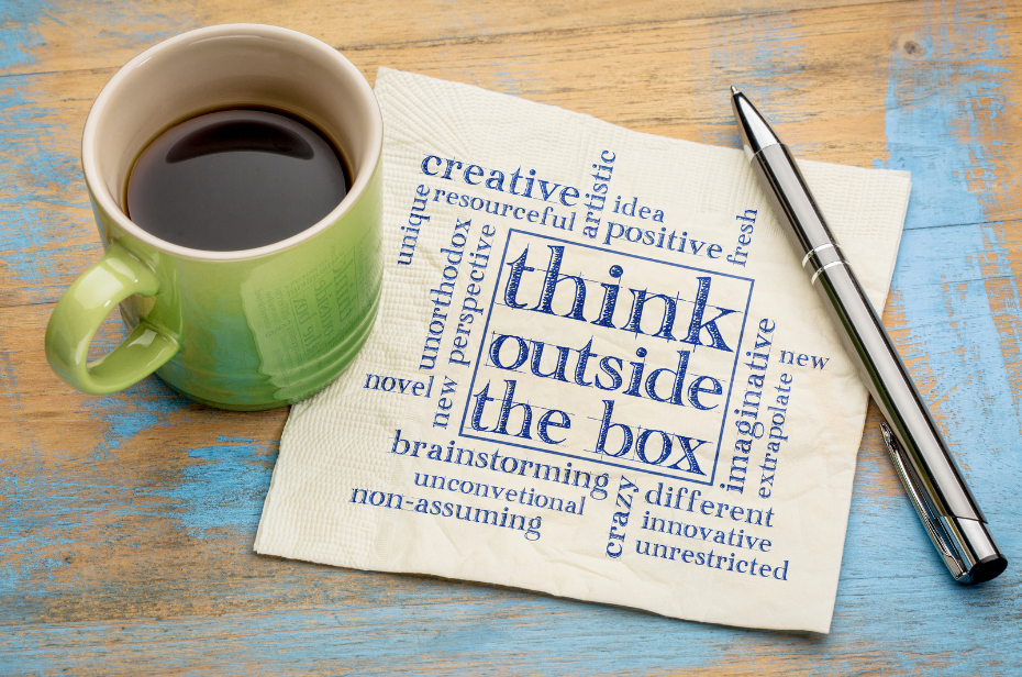 Coffee cup and pen on napkin with inspiring words like think outside the box, innovation, unrestricted