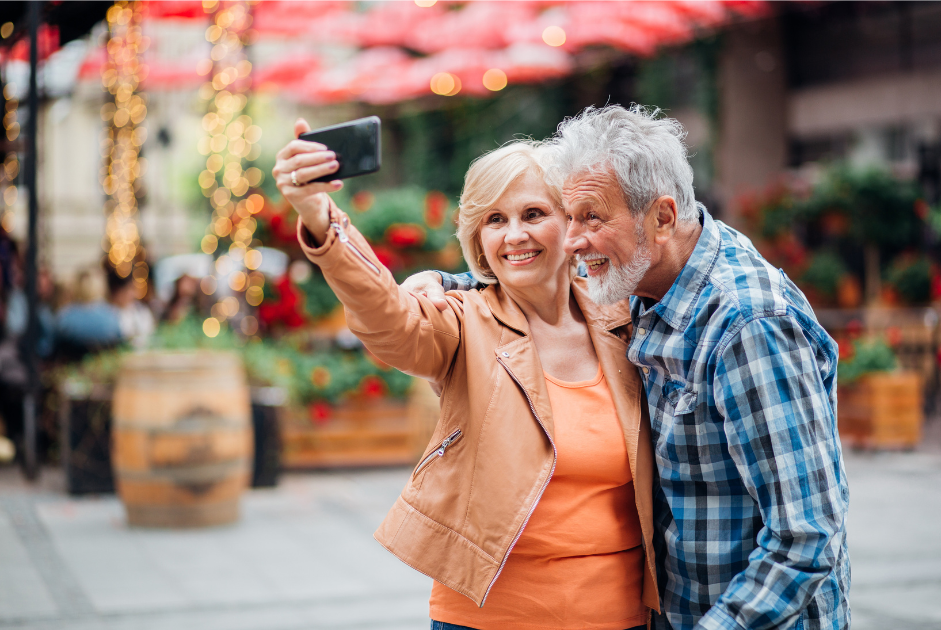 older couple with smiles in outdoor market taking a selfie