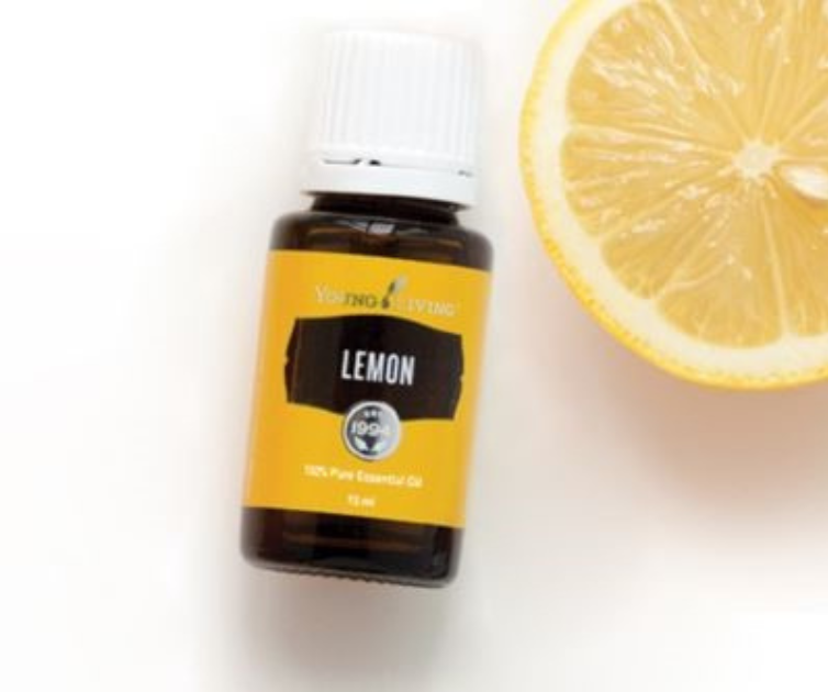 Young Living lemon essentail oil bottle sitting in front of a slice of lemon