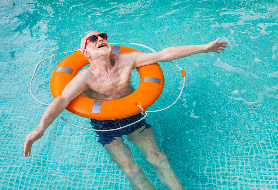 smiling elderly man in life preserver floating in a swimming pool .