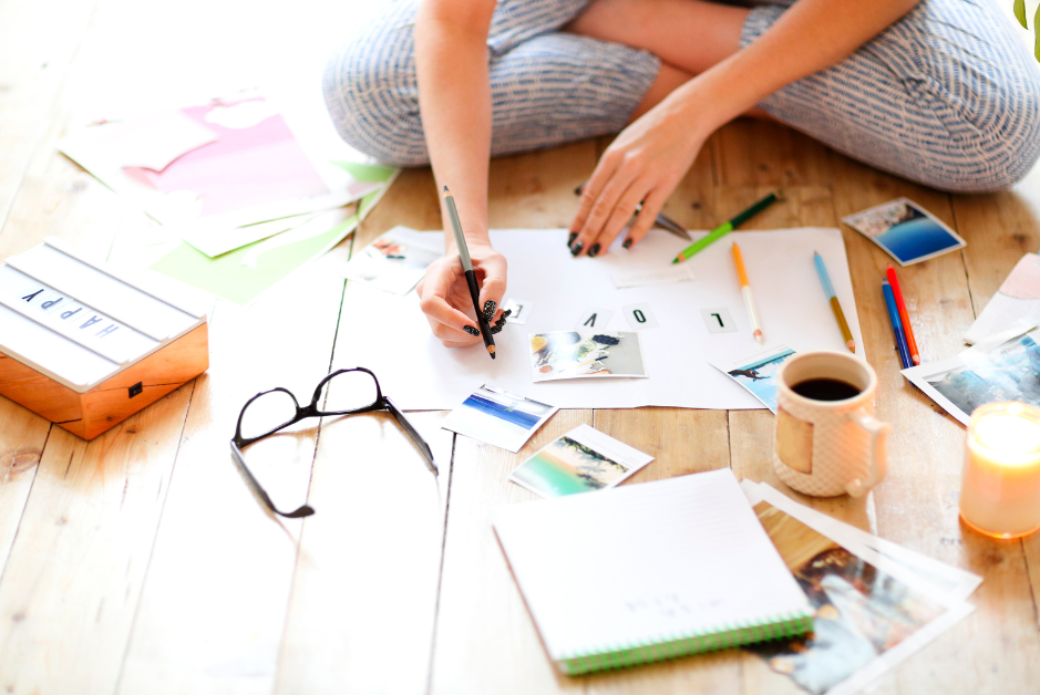 person sitting on the floor with supplies and coffee creating a journal entry and vision board journal page