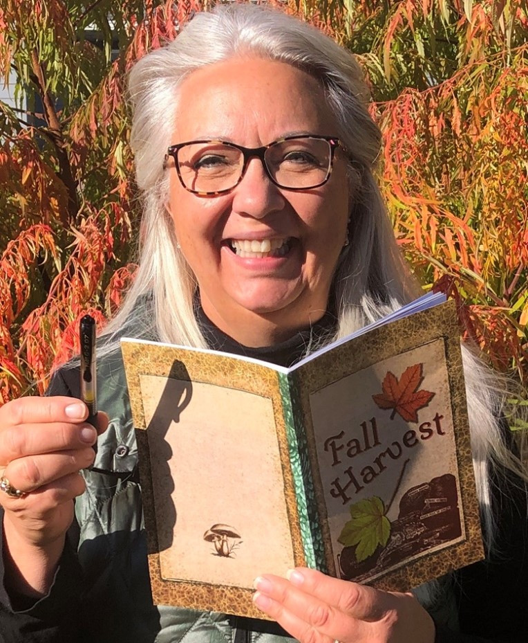 Lisa holding a Fall Harvest journal and pen in front of a fall sumac bush for post Top 2 Ways to Celebrate Fall: Adventure and Reflection 