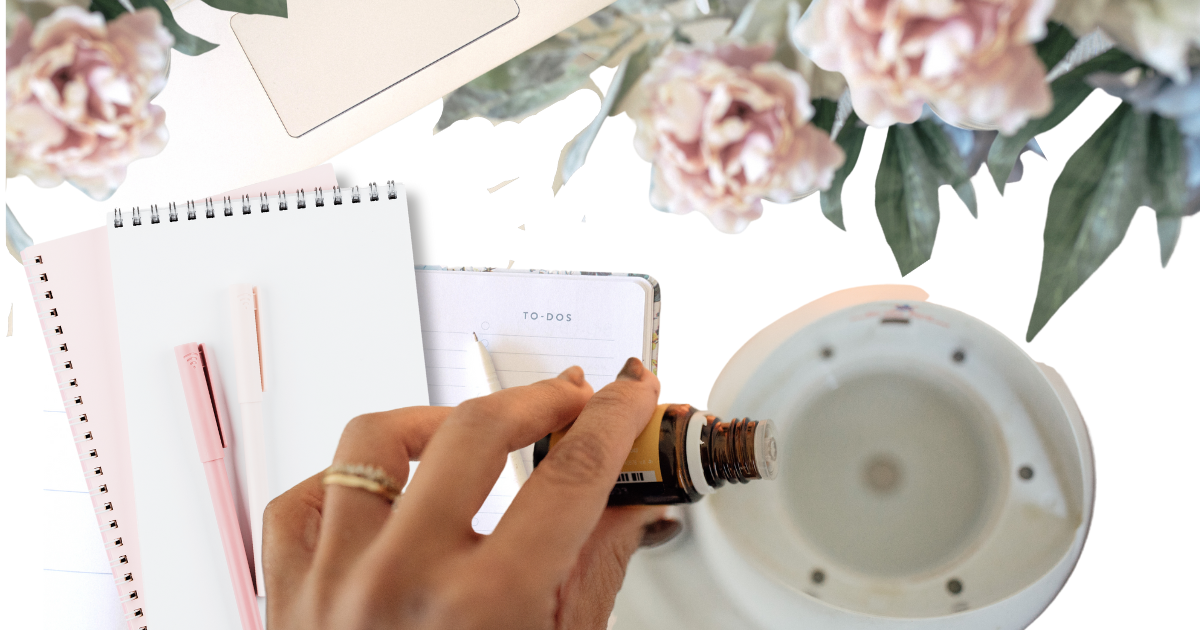 Hand dropping essential oils into a diffuser next to a journal and pen for post titled Journal Prompts to Unlock Creativity, Clarity, and Focus!