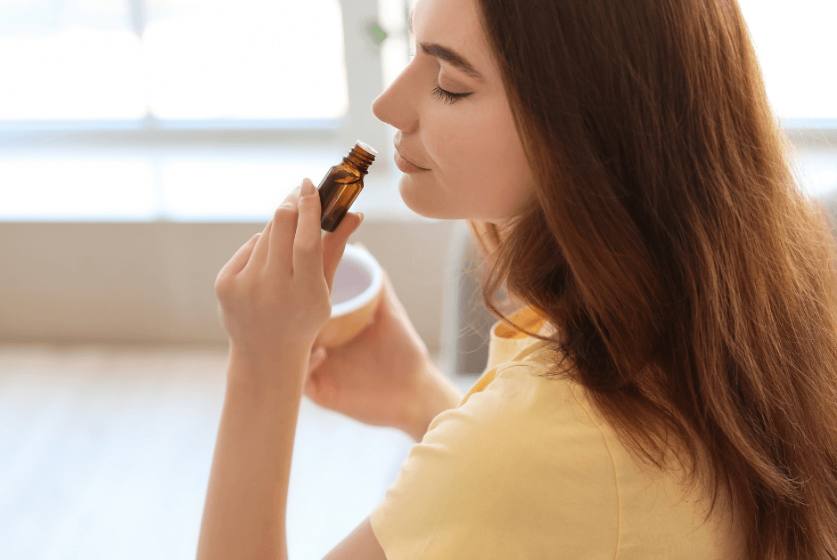 woman smelling an essential oil directly from the bottle for a post titled 5 Reasons to Diffuse Essential OIls Every Day!