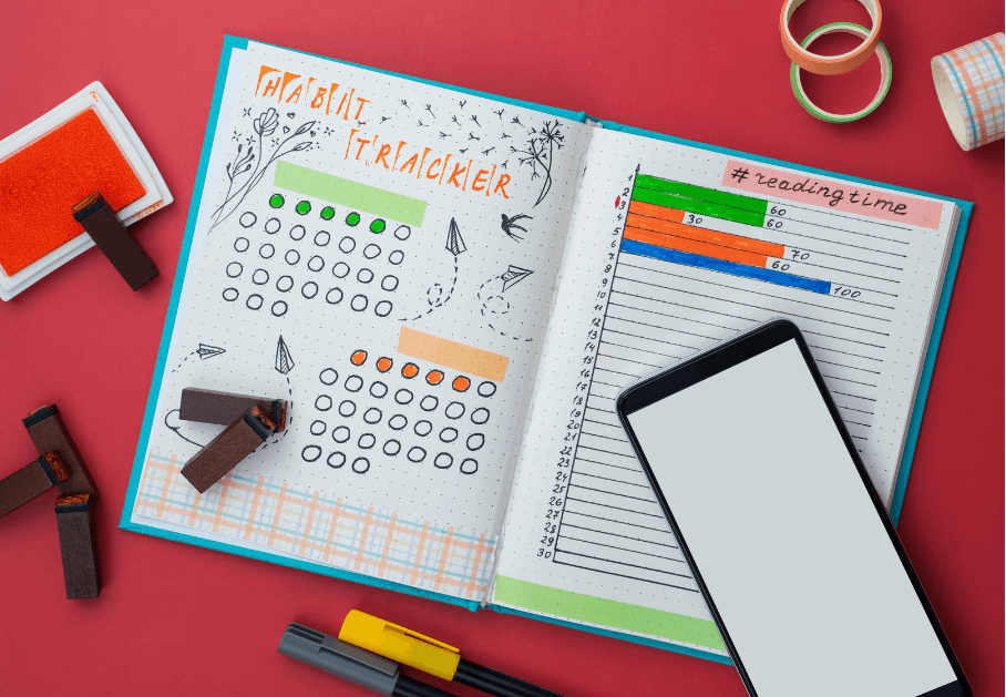 Open bullet journal with calendar like colored in circles, a time chart, colors and a phone for for a post titled4 Types of Journals: Which One Fits Your Style? 