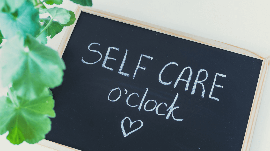 A chalk board sign that says, "Self Care o'clock' with a heart and a few plant leaves for blog post titled How to Prioritize Self-Care in a Hectic Day