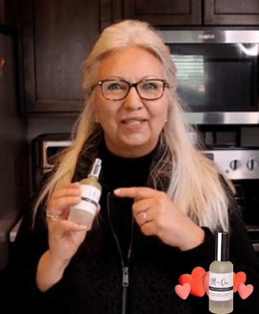 Lisa Compton holding a bottle of linen spray after making the DIY for a video  for blog post titled A bottle of Myrrh, Peace & Calming, and Clary Sage essential oils for blog post titled Linen Spray DIY: "You're still the one!"
