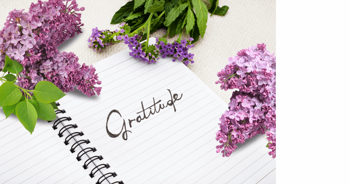 lilac blossom cuttings lying next to an open journal with the word Gratitude written on the page for post titled 6 Spring Journal Prompt Themes for New Beginnings
