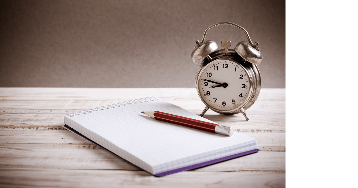 An alarm clock sitting on a desk next to an open journal with a red pencil sitting on top of the journal for post titled  7 Hidden Journaling Hurdles: Uncovering Why Many Hesitate to Start 