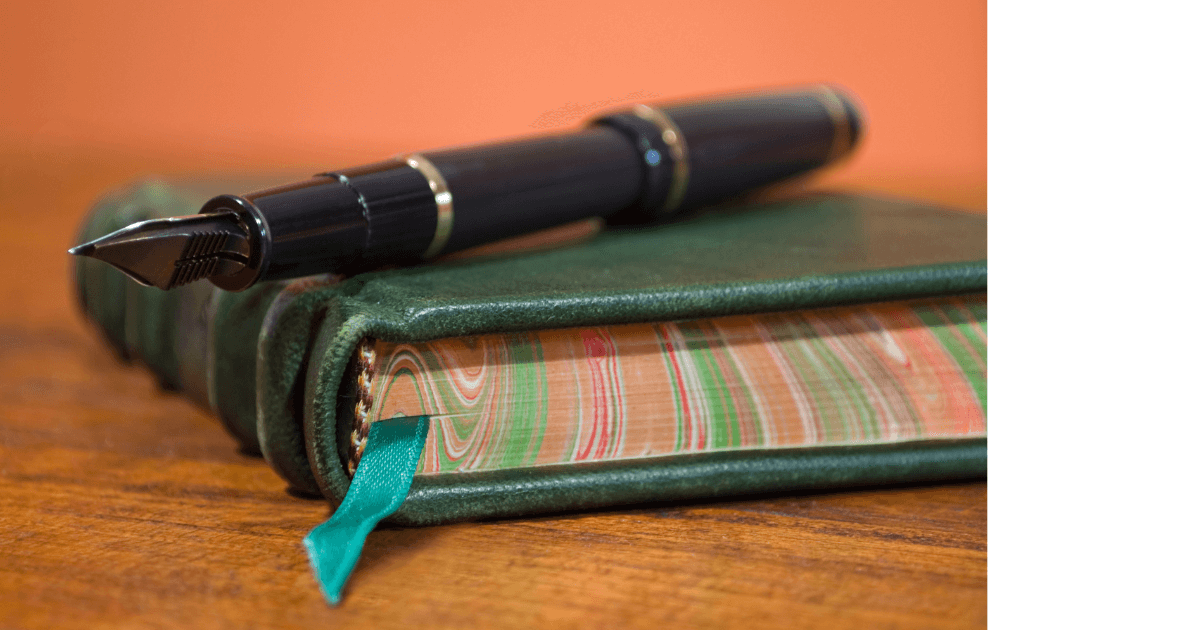 A green, leather, hand-made journal with marbled foredges and a fountain pen sitting on a table for post titled  7 Hidden Journaling Hurdles: Uncovering Why Many Hesitate to Start 