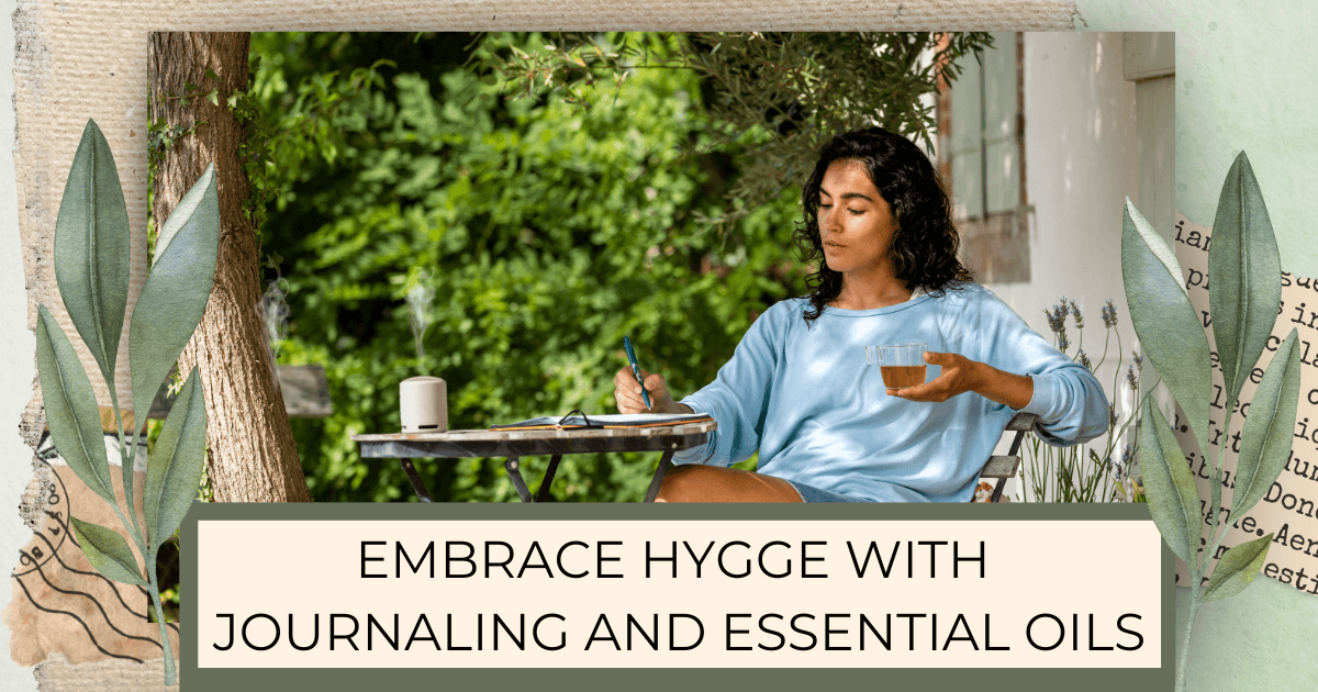 A woman sitting outside journaling at a table while holding a glass cup of tea and a diffuser is going on the table for post titled Embrace Hygge with Journaling and Essential Oils 