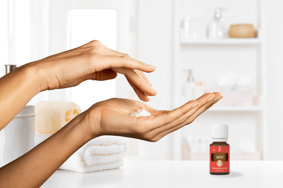 two hands with lotion in the palm of one hand and the other hand ready to mix in the drops of Raven essential oil in a bright white room for a blog post titled Top 5 Ways We Use Raven™ Essential Oil