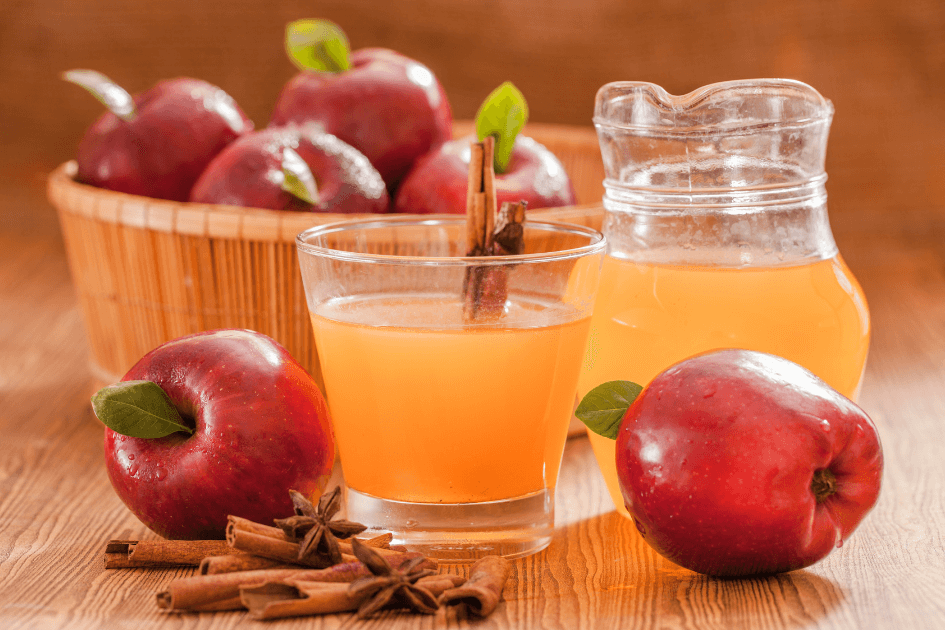 Red apples in a bowl near a pitcher and glass of apple cider with cinnomon stick in and around or a Bound to Journal blog post titled Fall Aromatherapy: 5 Seasonal Diffuser Recipes 