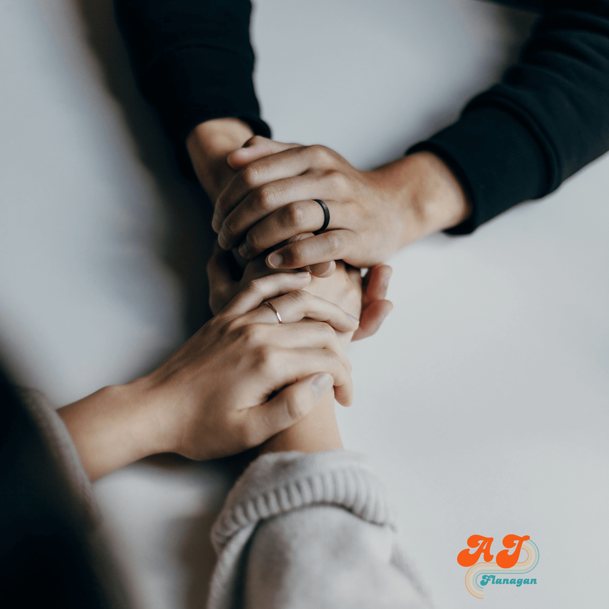 Two people holding hands across a table in a supportive manner