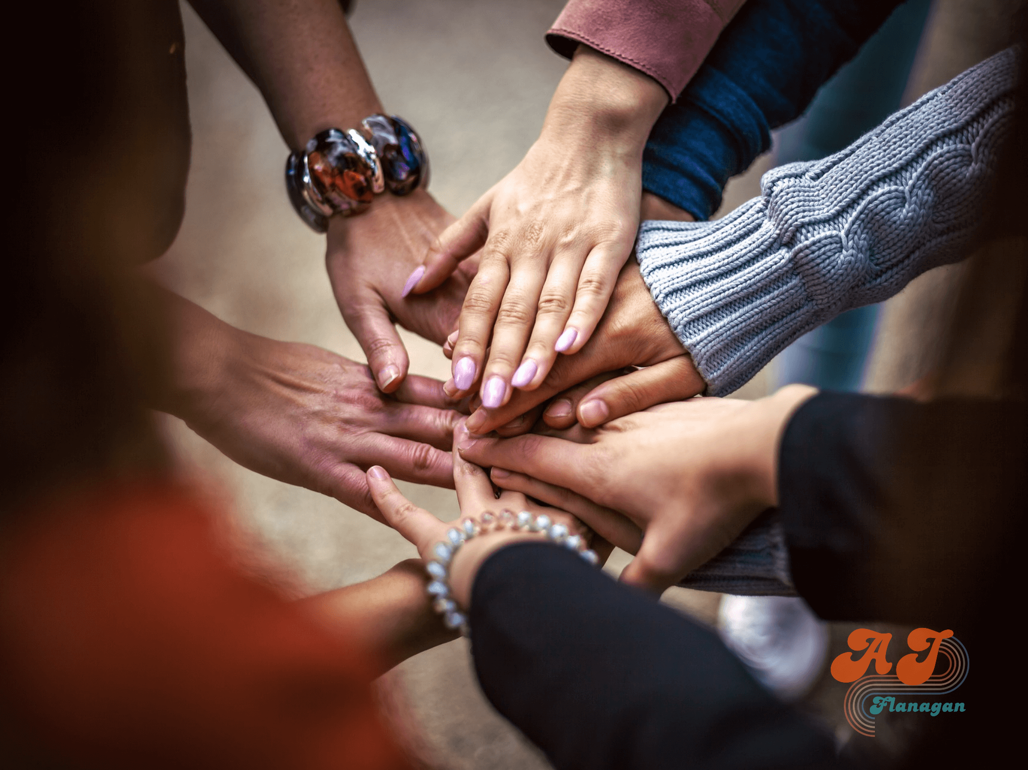 Nine hands reaching into the center in a show of team support