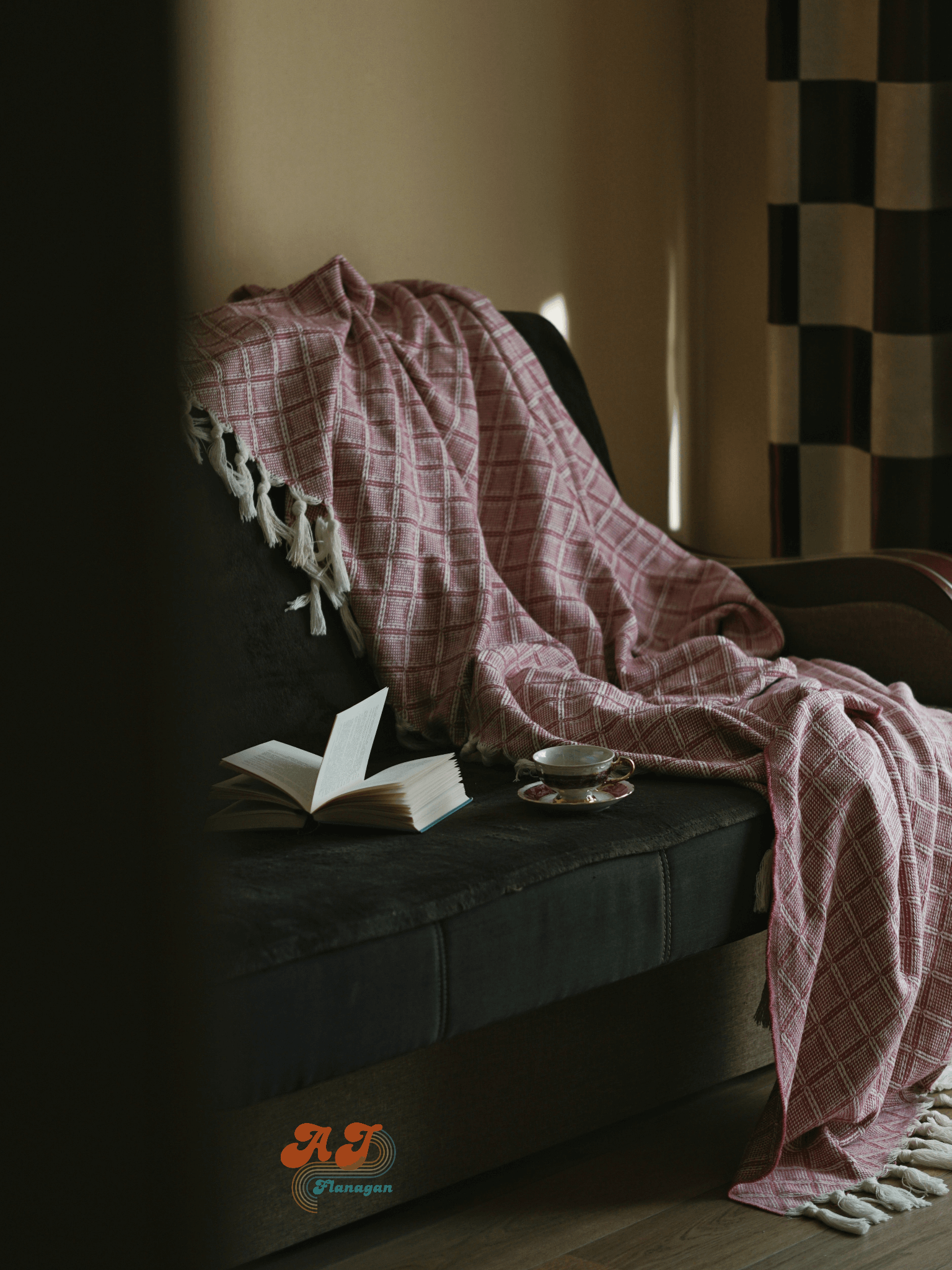  A blanket, hot cup of tea, and an open book by an empty chair