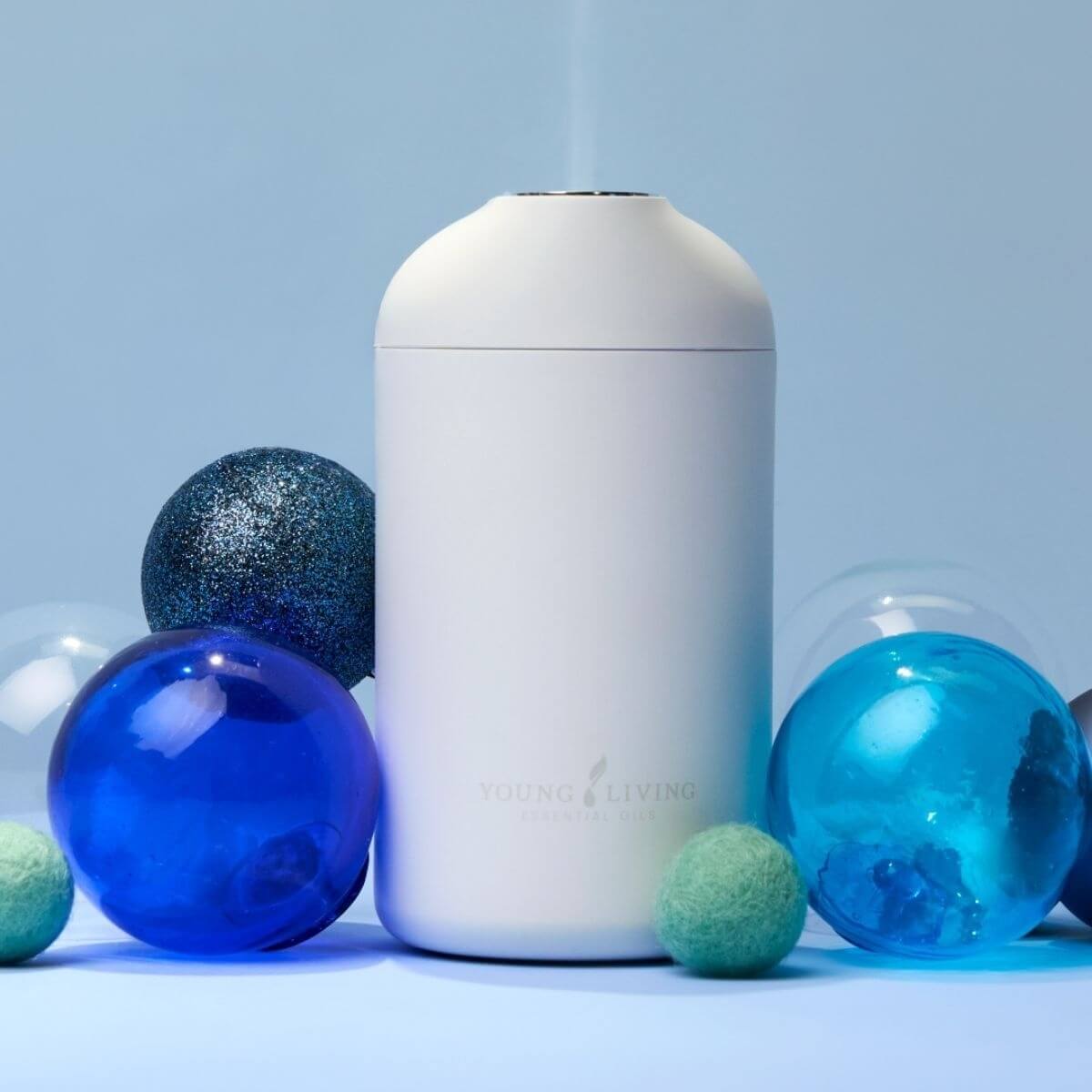 Young Living™ Wanderful Diffuser holiday display with blue and green ornaments — Small Business Saturday offer — House of Dawning seasonal wellness guide.