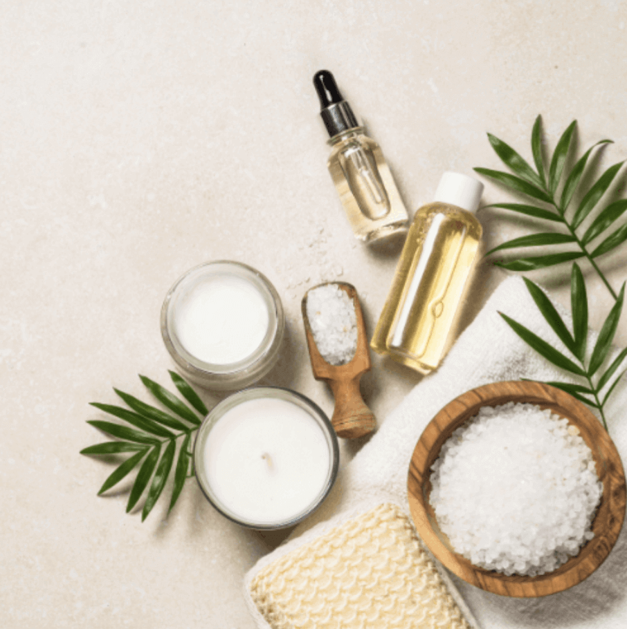 Cozy wellness flatlay with essential oils, bath salts, candle, botanical greenery, and soft linens — gentle self-care imagery for Tip Tuesday™ natural living rituals.