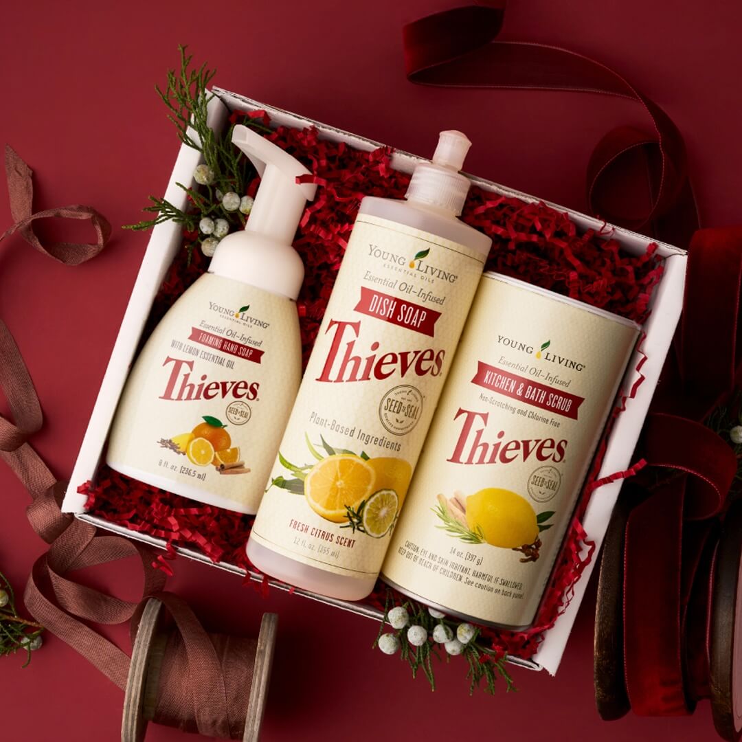 Thieves® Home Gift Set — boxed natural home-care collection featuring Thieves® Dish Soap, Thieves® Kitchen & Bath Scrub, and Thieves® Foaming Hand Soap. Holiday gift bundle displayed in red crinkle paper.