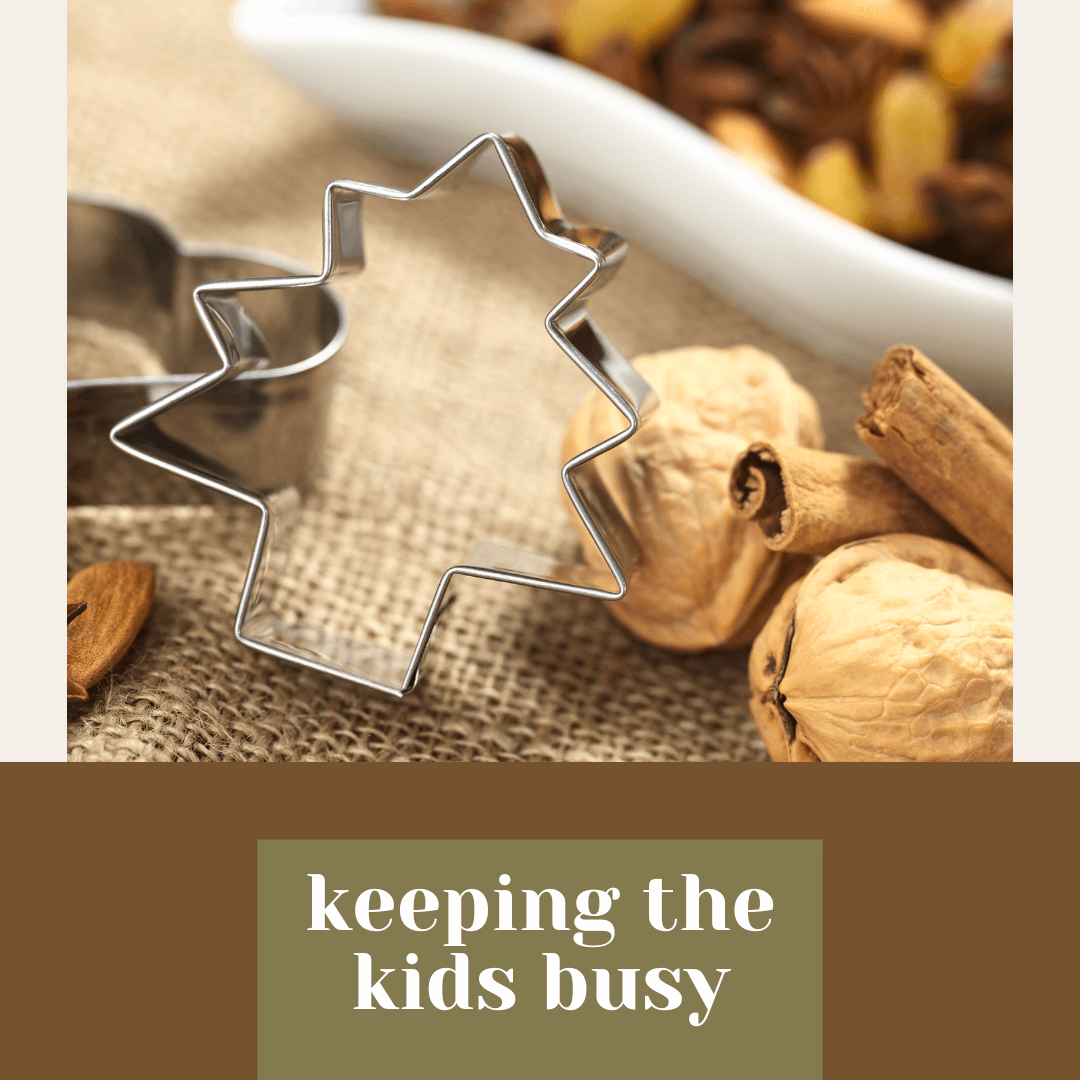  Tree-shaped cookie cutter on burlap surrounded by walnuts, cinnamon sticks, and holiday spices, with the words ‘keeping the kids busy’ below.