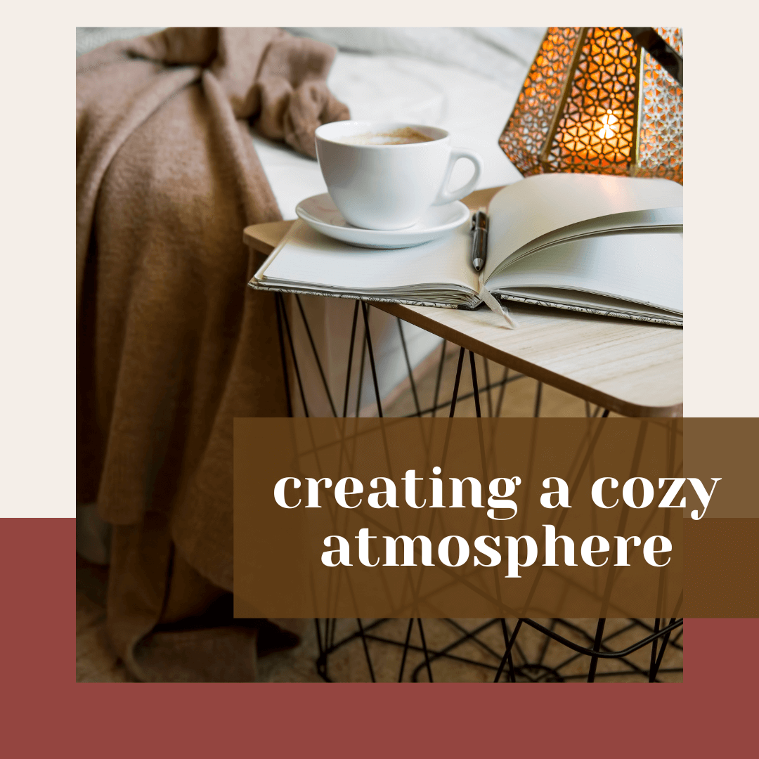  Cozy bedside scene with an open notebook, pen, and cup of coffee beside a glowing lamp and soft brown blanket, with the words ‘creating a cozy atmosphere.